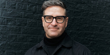 Portrait of Charles Nix wearing a black shirt in front of a black brick background cropped 16x9.