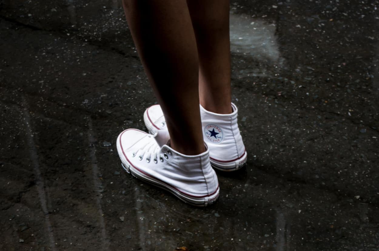 woman standing in water wearing white converse