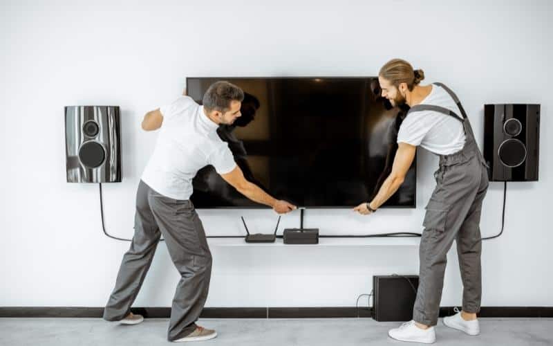 zwei Männer installieren einen Fernseher an der Wand
