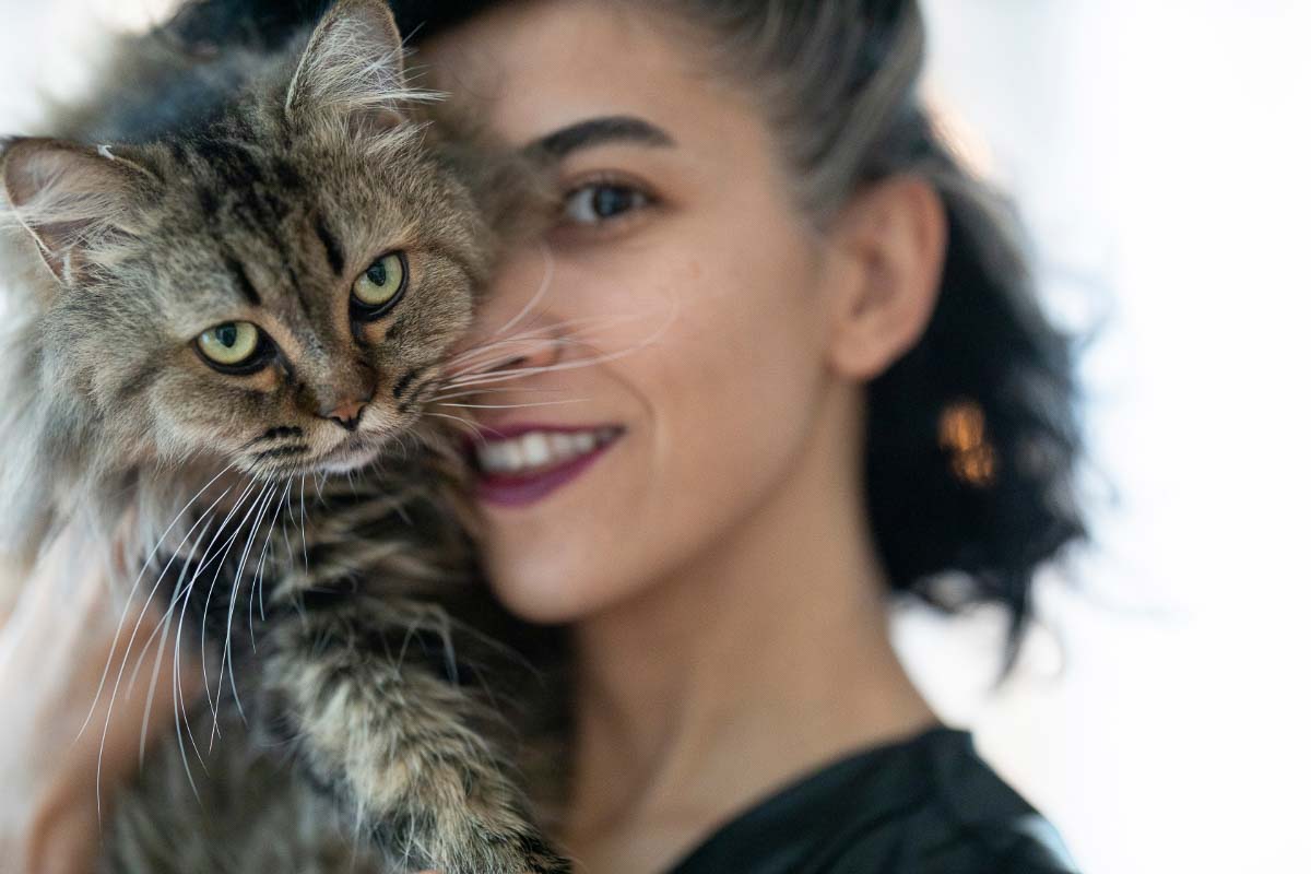 Frau kuschelt mit Tabby-Katze.