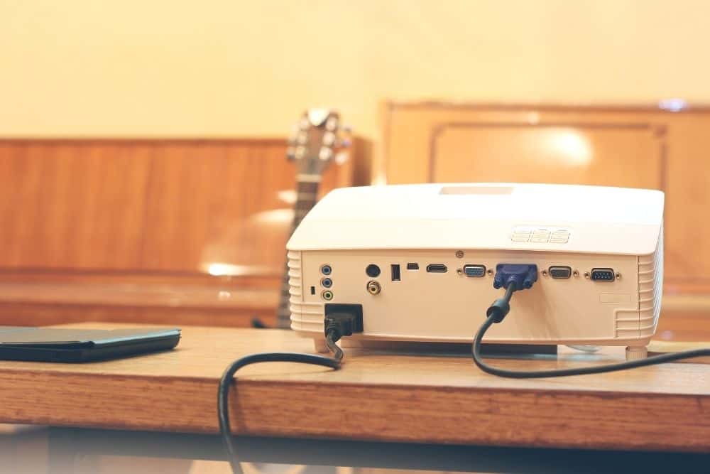 ein Projektor auf einem Tisch mit angeschlossenem VGA-Kabel